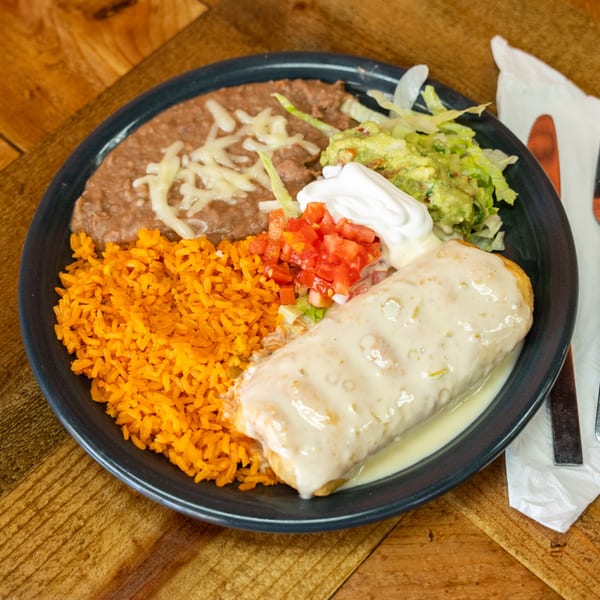 A Carnales Taqueria chimichanga plate with rice, refried beans, guacamole, sour cream, and pico de gallo.