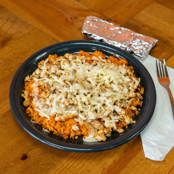 Mexican chicken and rice dish topped with melted cheese, served on a dark plate.